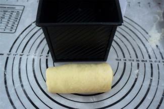 取一块面团，擀成长舌状，宽度与模具相当，卷起，收口朝下，放入模具中，每个模具放入3块面团。