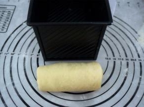 取一块面团，擀成长舌状，宽度与模具相当，卷起，收口朝下，放入模具中，每个模具放入3块面团。