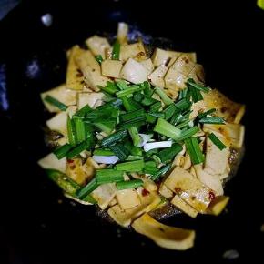 加入千页豆腐，加入生抽，少许盐，一点温水翻炒至千页豆腐膨胀变大，放入青椒，蒜苗翻炒
