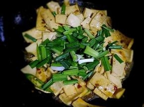 加入千页豆腐，加入生抽，少许盐，一点温水翻炒至千页豆腐膨胀变大，放入青椒，蒜苗翻炒