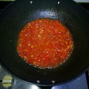 放入西红柿丁，用铲子边压边翻炒，加入适量酱油，加入水煮至西红柿成泥状