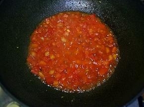 放入西红柿丁，用铲子边压边翻炒，加入适量酱油，加入水煮至西红柿成泥状