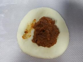 6．取其中一个面团压扁，中间放入馅料的1/3。