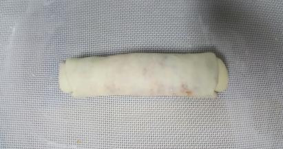 9．将擀长的椭圆形面皮，从上而下卷起。