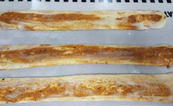 11．用手将饼胚压扁，压扁后用擀面杖擀长，用手捏住两边再抻长。