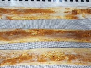 11．用手将饼胚压扁，压扁后用擀面杖擀长，用手捏住两边再抻长。