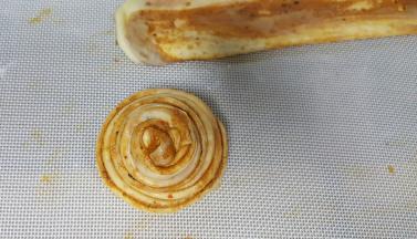 14．用左手大拇指和食指捏住饼胚的一头，另一只手绕圈圈，将其全部绕住，尾部藏在底下压住。