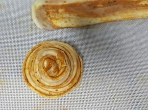 14．用左手大拇指和食指捏住饼胚的一头，另一只手绕圈圈，将其全部绕住，尾部藏在底下压住。