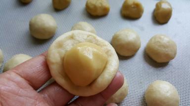 5．取一份水油皮面团，捏成扁圆形，包一份油酥进去。