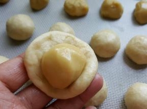 5．取一份水油皮面团，捏成扁圆形，包一份油酥进去。