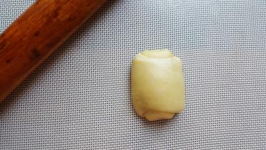 11．将卷好的面团，取一个压扁擀开成长条。