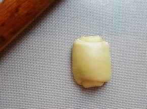 11．将卷好的面团，取一个压扁擀开成长条。