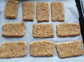 13．全部擀好后，上刷全蛋液，粘一层熟的白芝麻，放在铺有烘焙纸的烤盘上。