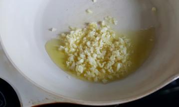 3．在揉面的同时，我们可以酱料，将橄榄油放在不粘锅内，加入大蒜头碎，炒到焦黄。