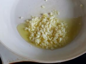 3．在揉面的同时，我们可以酱料，将橄榄油放在不粘锅内，加入大蒜头碎，炒到焦黄。