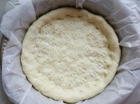 14．将披萨底移动到模具中，再次整理一下形状后，底部用叉子叉小孔。