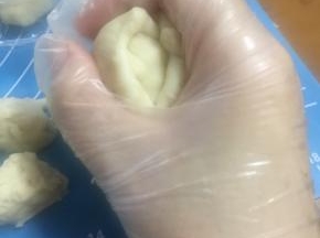将油皮团捏扁，放入一个酥皮团，包好