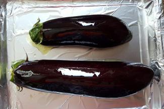 1.两根茄子洗净去蒂，用厨房纸将水分擦干，表面刷花生油，放入铺有锡纸的烤盘上。