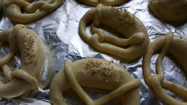 16．将烘焙碱放入温水中进行融化，把冻好的面包胚放入其中浸泡20-30秒，捞出放入铺有锡纸的烤盘中，（这一步操作最好戴手套，因为烘焙碱有强烈的腐蚀性）面包上面用锋利的刀片划一个切口，撒一些芝麻作为装饰，如果有海盐就更好了。