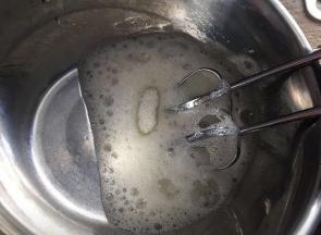 用电动打蛋器打发，低速打发至粗泡的时候，放入三分之一的糖，中速继续打发