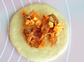 取一个面团，擀成片状，包入内馅，捏紧封口。