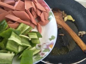 倒入切好的火腿和青椒，中火炒两分钟左右