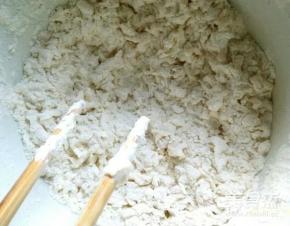 不时移动一下盆子，不要让水滴总滴在一个地方。继续拌，上层会出现很多疙瘩，但是下层还是面粉。把面盆轻轻颠动一下，像筛东西一样。把上层的疙瘩轻轻拨到一边。然后继续把下层的面粉拌成疙瘩。