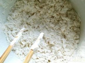 不时移动一下盆子，不要让水滴总滴在一个地方。继续拌，上层会出现很多疙瘩，但是下层还是面粉。把面盆轻轻颠动一下，像筛东西一样。把上层的疙瘩轻轻拨到一边。然后继续把下层的面粉拌成疙瘩。