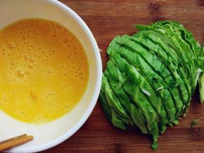 卷心菜洗净，横向切一半。也就是切顶部的一半，带粗根的部分在另外一半上。
切粗条（切得太细很容易软烂，丧失脆脆的口感）。鸡蛋加盐打散。