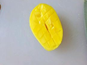 把芒果对半切开，用刀划十字