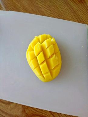 用手指朝上顶，用勺子把果肉剃下来。