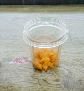 在把芒果肉放入料理机中。