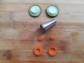 用圆嘴裱花嘴的大头在蛋白上印出2个大圆，用裱花嘴的小头在胡萝卜上印出2个小圆