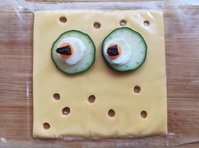 把眼睛部分摆到芝士上，用吸管在芝士片上戳几个孔