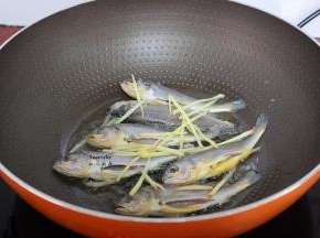 热锅，倒油，放入腌制好小黄鱼小火煎至金黄色，鱼上面撒上生姜丝去腥；