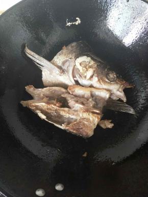 铁锅放油烧热后放入鱼头两面煎黄。