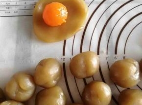 将蛋黄包入莲蓉中，揉成圆形。