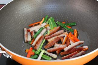 叉烧切长条，加入锅中翻炒；