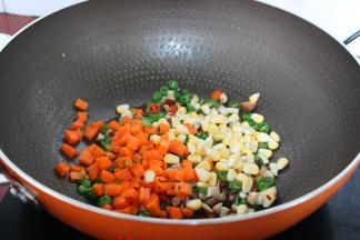 加入胡萝卜、玉米粒继续翻炒；