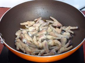热锅，倒入适量的油，油温热了，倒入鸡爪炸至微黄；PS：炸的时候记得盖上盖子，以防油溅出烫伤。