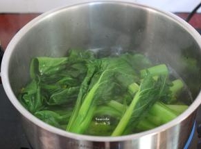 清水煮沸，放入生姜，汆烫菜心，捞出菜心放入盆中