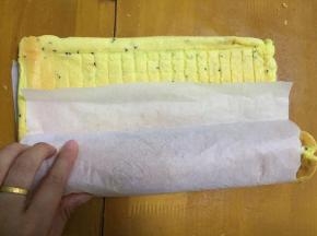 待蛋糕温热时，撕掉油纸，重新拿一张油纸放在上面，翻面，卷起