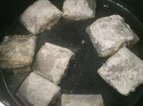 腌制好的带鱼段裹一层干淀粉。
平底锅内倒入适量食用油，放入带鱼段，小火煎制。