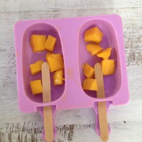 雪糕模具中放入一些芒果颗粒，插上木棍。