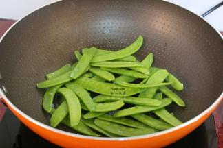 炒过腊肠的油锅，荷兰豆倒入锅中，爆炒片刻；