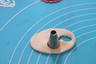 用最小号的裱花嘴背面切割出白色的胡子部分，在黄色翻糖上切割出耳朵。