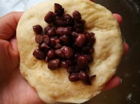 取出面团拍扁，放入蜜红豆