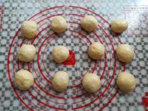 面团取出轻压排气，平均分成12个小面团，滚圆盖上保鲜膜松弛15分钟