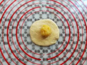 取一个面团用擀面杖擀平放上奶黄馅