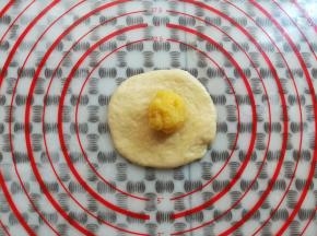 取一个面团用擀面杖擀平放上奶黄馅